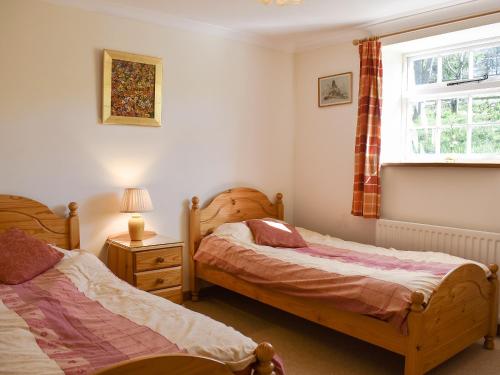 a bedroom with two beds and a window at Mill Pond Cottage in Bere Regis