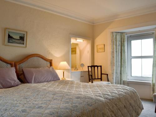 a bedroom with a large bed and a window at White Cottage in Lower Largo