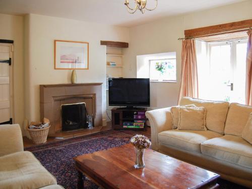 uma sala de estar com um sofá e uma televisão em Park House em Harlaxton