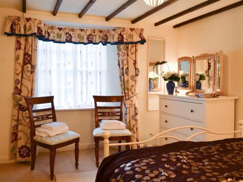 a bedroom with a bed and two chairs and a window at Croft House in Broughton in Furness