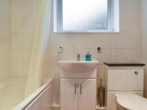 łazienka z umywalką, toaletą i oknem w obiekcie Croft Cottage w mieście Braithwaite