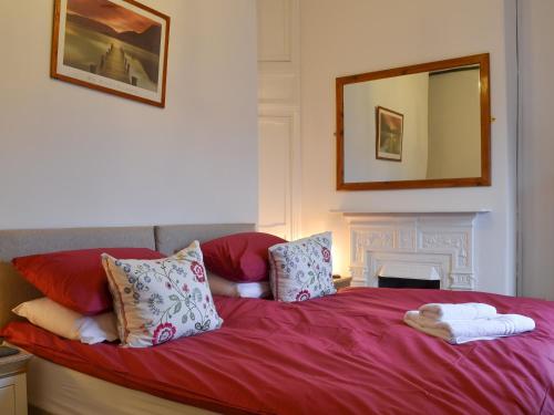 sypialnia z czerwonym łóżkiem z poduszkami i lustrem w obiekcie Croft Cottage w mieście Braithwaite