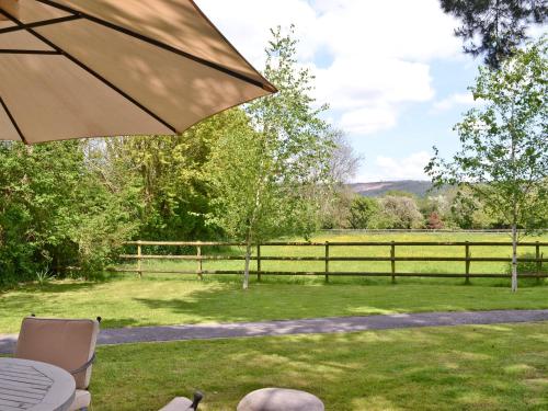 een patio met een parasol, een veld en een hek bij Strawberry Lodge in Cheddar