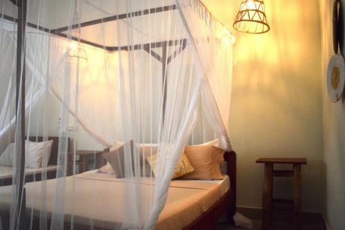 sypialnia z łóżkiem z baldachimem i białymi zasłonami w obiekcie Maryam Garden Apartments & Villa w mieście Bwejuu