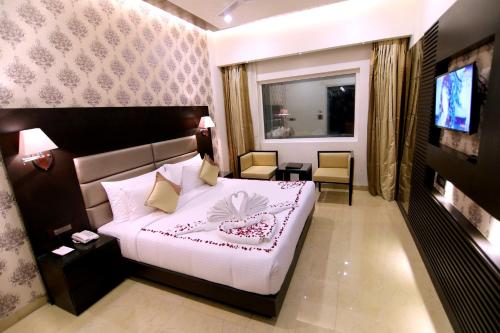 a hotel room with a bed and a television at Udman Hotel Haridwar in Haridwār