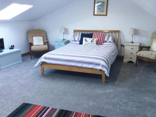 a bedroom with a large bed and two chairs at Beudy Isaf in Llangybi