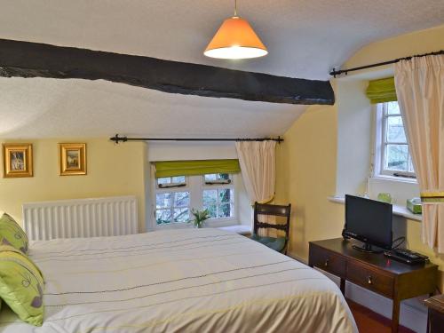 a bedroom with a bed and a tv and windows at Toms Cottage in Dalton in Furness