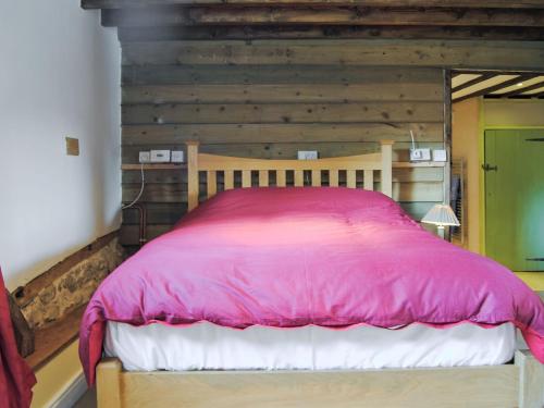 a bed in a room with a wooden wall at Hirros Hall Longhouse in Llanerfyl