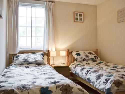 a bedroom with two beds and a window at Mill Pond Cottage in Cromford