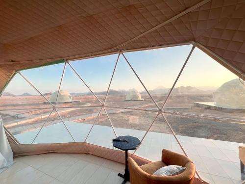 a room with a view of the desert from a glass window at Wadi Rum stargazing camp in Wadi Rum