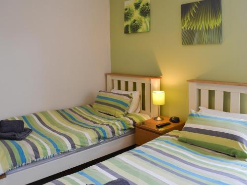 a bedroom with two beds and a table with a lamp at Bay House in Filey