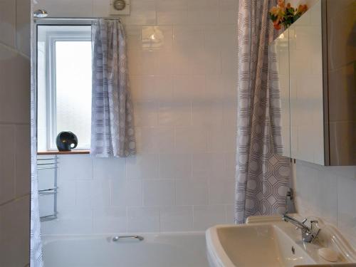 a bathroom with a tub and a sink and a window at Alpine Lodge in Burgh le Marsh