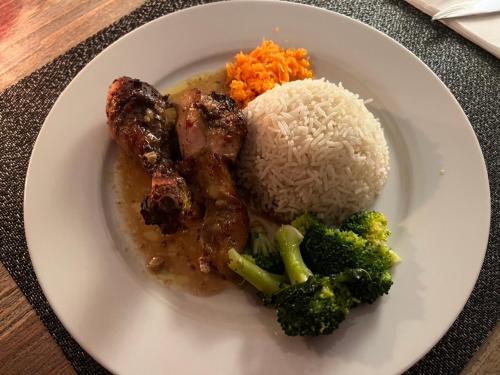 a white plate of food with rice and broccoli at La Chanterelle - Mountain Lodge in La Côte dʼArbroz
