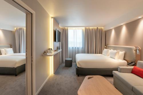 pokój hotelowy z 2 łóżkami i kanapą w obiekcie Holiday Inn Express - Marne-la-Vallée Val d'Europe, an IHG Hotel w mieście Bailly-Romainvilliers