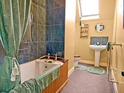 a bathroom with a tub and a sink and a toilet at Lochside Stable Hse in Town Yetholm