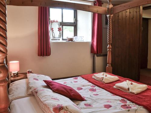 a bedroom with a canopy bed with red curtains at Weycroft Hall Cottage in Axminster