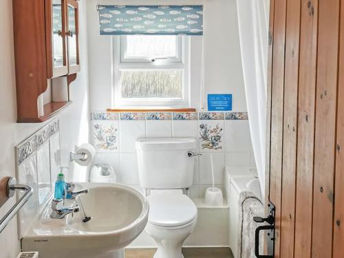 a bathroom with a toilet and a sink and a window at Owl Barn in Burmarsh