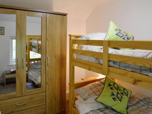 a bedroom with two bunk beds and a mirror at Capel Fawnog Mawr in Talsarnau