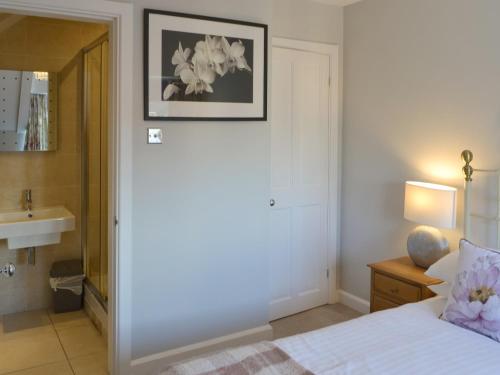 1 dormitorio con cama, lavabo y espejo en Littlecroft, en Alnmouth