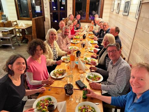 a group of people sitting at a long table eating food at La Chanterelle - Mountain Lodge in La Côte dʼArbroz