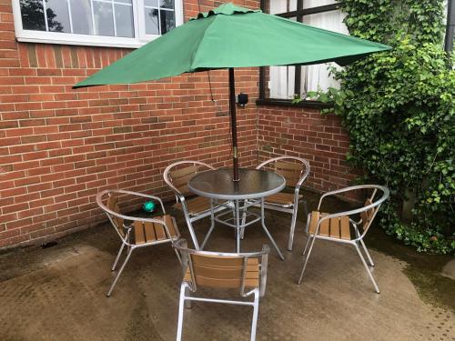 stół i krzesła z zielonym parasolem w obiekcie High rd hideaway w mieście Warmsworth