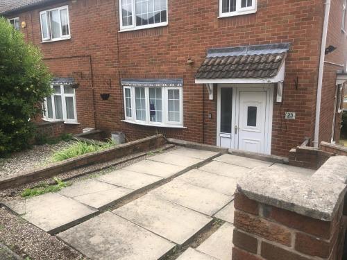 a brick house with a driveway and a white door at High rd hideaway in Warmsworth