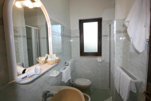 La salle de bains est pourvue d'un lavabo, de toilettes et d'un miroir. dans l'établissement Residence Club Barbara, à Ostuni