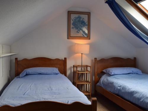 a bedroom with two beds and a lamp in it at The Blacksmith Shop in Shorwell