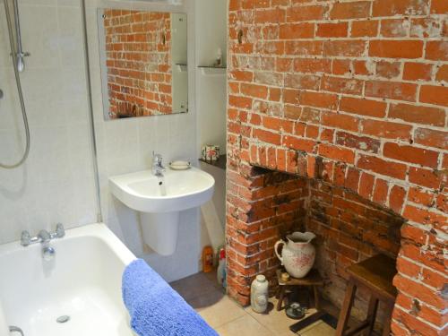 FordwichにあるBow Cottageの白い洗面台とレンガの壁が備わるバスルーム