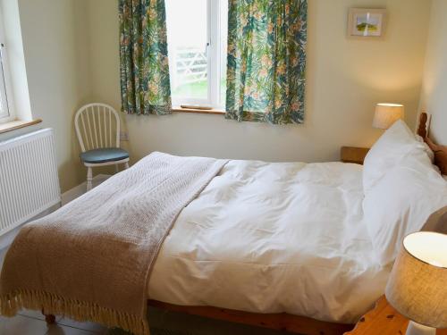 um quarto com uma cama, uma janela e uma cadeira em Freefolk Cottage em Polzeath