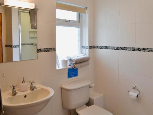uma casa de banho com um WC, um lavatório e um espelho. em Freefolk Cottage em Polzeath
