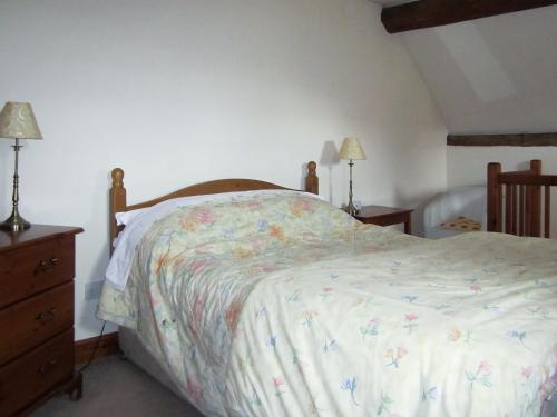 a bedroom with a bed and a dresser and lamps at Garden Cottage in Hasfield