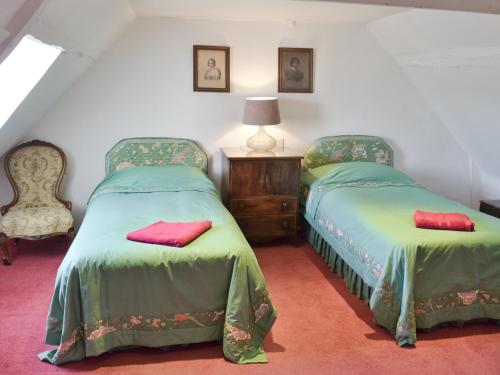 a bedroom with two beds with green sheets and red pillows at Red Lion Corner in Lavenham