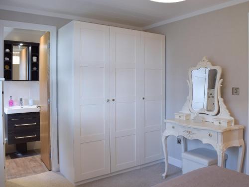 a white bedroom with a dressing table and a mirror at Seatrees in Corton