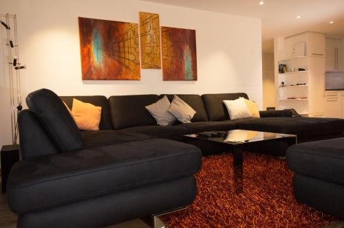 - un salon avec un canapé noir et une table dans l'établissement Residence Bellevue, à Zermatt