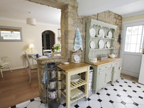 una cocina con armarios blancos y una mesa con platos en The Retreat Lulworth en West Lulworth