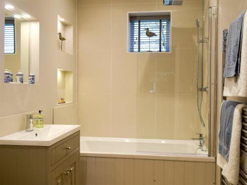 ein Bad mit einer Badewanne, einem Waschbecken und einer Dusche in der Unterkunft The Coach House in Tattingstone