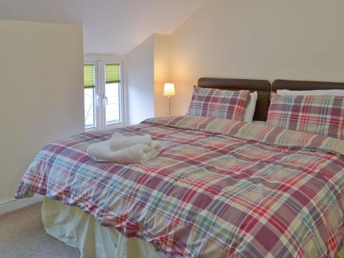 ein Schlafzimmer mit einem Bett mit einer karierten Decke in der Unterkunft Hare Lodge in Lamerton
