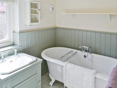 a bathroom with a tub and a sink at Turnstone Cottage in Sheringham