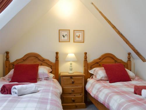 a bedroom with two beds and a table with a lamp at Russett Cottage-19745 in Peasmarsh