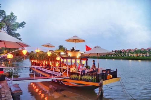 a boat with people sitting on it on the water at Little Riverside Hoi An . A Luxury Hotel & Spa in Hoi An