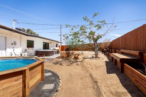 a backyard with a pool and benches and a house at 2 Min To Dt, Fire Pit, Hot Tub, Fully Fenced in Joshua Tree
