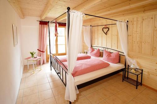 シュヴァンガウにあるJägerhof und Jägerstadelのベッドルーム1室(天蓋付きベッド1台、赤い枕付)