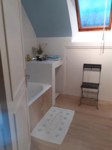 een kleine witte kamer met een stoel en een raam bij La Voile Bleue in La Trinité-sur-Mer