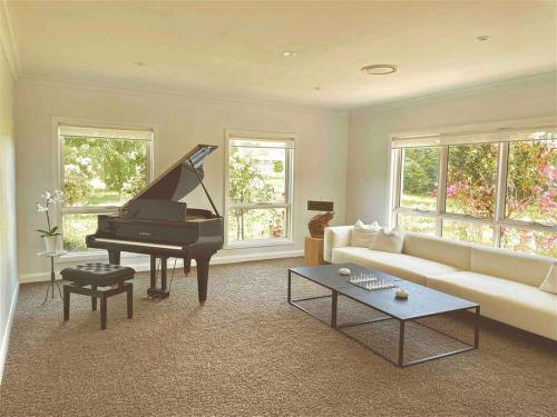 a living room with a piano and a couch at The York Residence in Hartley NSW - Newly Listed in Hartley