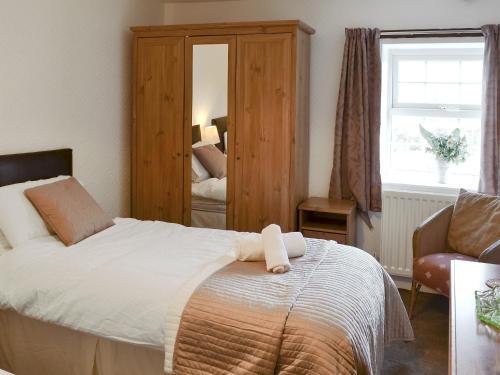 a bedroom with a bed and a chair and a mirror at Riverview in Frosterley