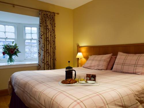 a bedroom with a bed with a tray of food on it at Inn Cottage in Glendevon