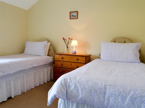 a bedroom with two beds and a dresser with a lamp at East Bridge End Farm in Frosterley