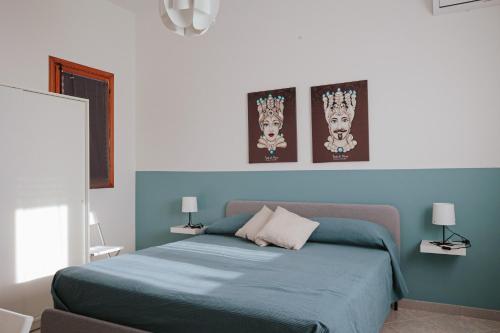 a bedroom with a blue bed with three pictures on the wall at Makira in Terrasini