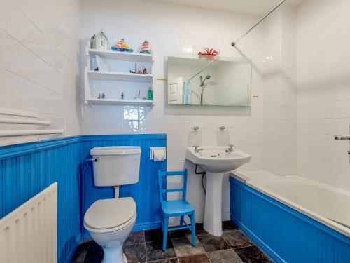 a blue and white bathroom with a toilet and a sink at Leeward Cottage in Wells next the Sea